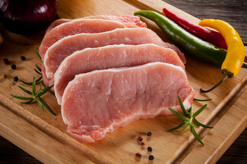 Raw pork chops on cutting board and vegetables 