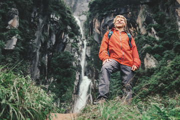 Young tourist man stay in mountain near the waterfall