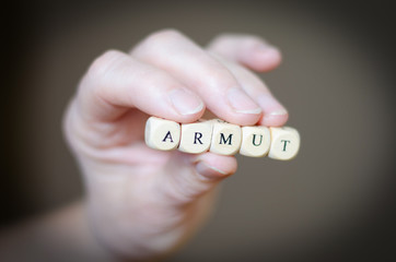 Armut, arm, kein Geld, Buchstabenwürfel zwischen den Fingern, symbolisch