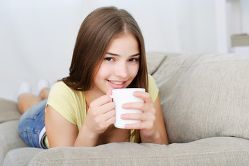 young woman sitting on couch and drinking coffee