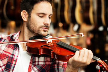 In The Musical Store. Man is playing violin.