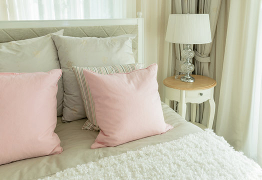 cozy bedroom interior with pink pillows and reading lamp on bedside table