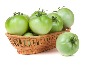 unripe green tomatoes in a wicker basket isolated on white background