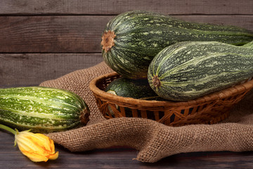 green zucchini or courgettes with a flower on sackcloth wooden background