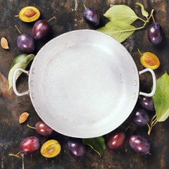 Old bowl and plums on a rural background