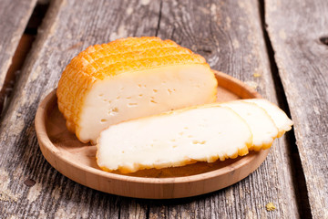 Home deliciouse smoked rustic cheese on old board.