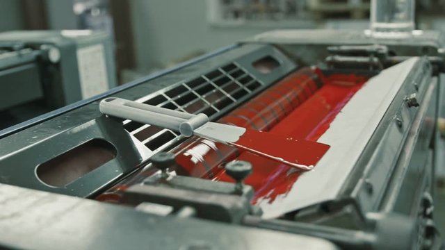 Polygraphy printing industry - red paint on ink roller, close up