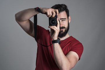 Desaturated portrait of photographer taking photo with dslr camera holding vertically over dark...