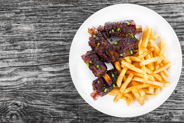 fried sticky ribs sprinkled with green onion with french fries