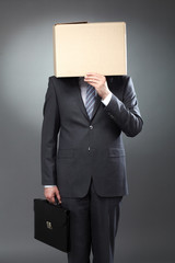 Conceptual image of unrecognizable person with box on the head and holding briefcase