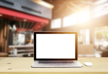 Laptop computer with blank screen on wood table in architect office