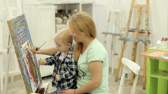 Cute little boy draws with mom in the Studio. The child learns to draw.