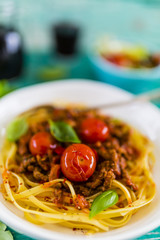 Delicious bavette pasta with bolognese sauce and fresh herbs on wooden table. Italian food.