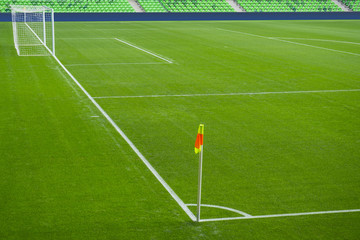 Football soccer field with white marks, green grass texture and corner flag.