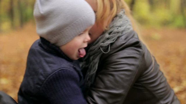 Happy child kissing his mother in autumn park.