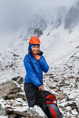 Woman in Helmet with backpack on Snow Covered Mountain Top Enjoying View.