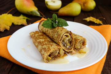 Fragrant sweet pancakes with caramelised pears on a white plate.