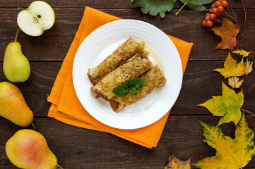 Fragrant sweet pancakes with caramelized pears on a white plate. The top view