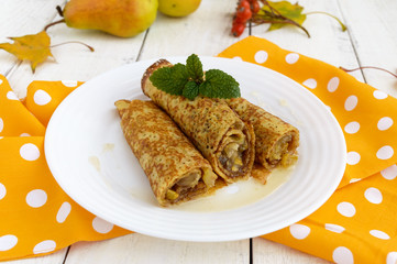 Fragrant sweet pancakes with caramelized pears on a white plate.