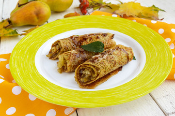 Fragrant sweet pancakes with caramelized pears and chocolate syrup and mint leaves on a white background. 