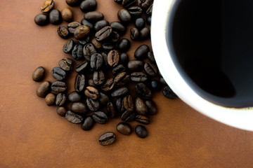 A cup of coffee and coffee beans. Brown background.