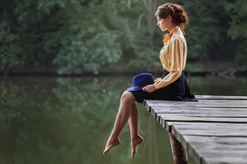 young woman sitting on wooden bridge