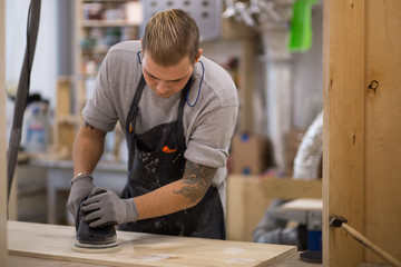 tattooed man polishes the Board. carpenter