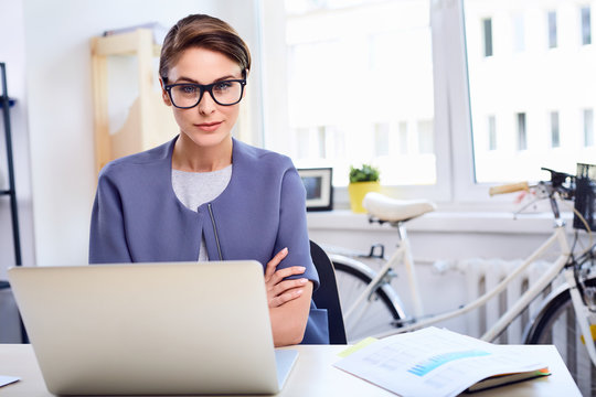 Portrait of confident businesswoman sitting by desk at office