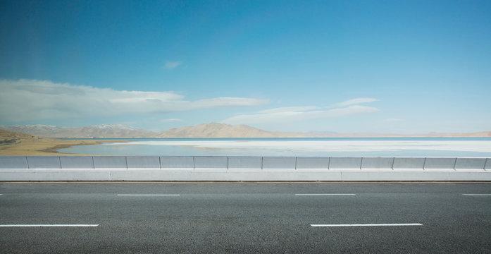 Empty Asphalt Road And Lake Mountain Background .