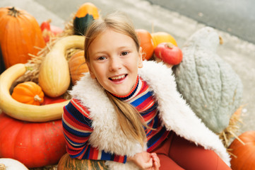 Fototapeta na wymiar Adorable little girl of 8-9 year old choosing halloween pumpkin on farm market