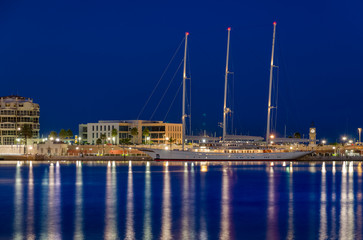 Fototapeta na wymiar Night lights of Tarragona port with beautiful long yacht, Spain