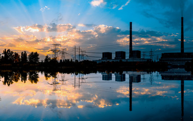 Coal-fired power plant at sunset and reflection in water.