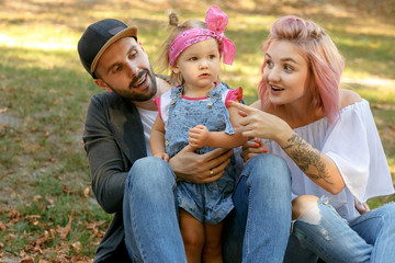 Stylish young mother with pink hair and tattoos on her hand show