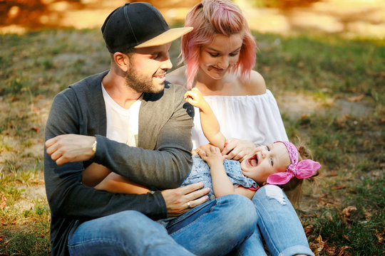 Stylish dad in black hat admires his little daughter while havin