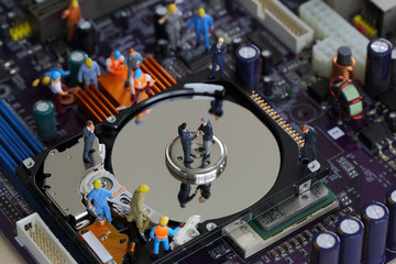 Obraz premium Selective focus of miniature businessman handshake on the disk of harddisk as teamwork, commitment, repair and industrial concept.