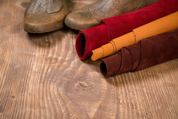 Leather in rolls and shoe lasts on wooden background. Leather craft. Copy space.