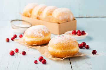 Delicious freshly baked doughnuts with powdered sugar and fruit jam on blue wooden background. Breakfast concept, Selective focus.