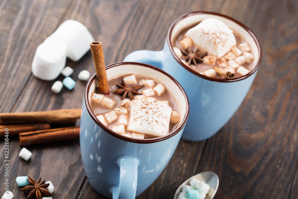 Wall mural blue cups of hot chocolate drink with marshmallows and cinnamon on dark wooden background. winter ti