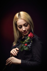 Beautiful young blonde woman with red rose on Valentine's Day