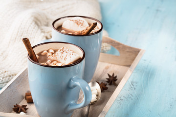 Blue Cups of hot Chocolate drink with Marshmallows and cinnamon on blue wooden background. Winter...