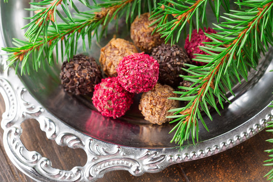 Assorted dark chocolate truffles with dried strawberry pieces and chopped hazelnuts on rustic wooden background, selective focus. Christmas time, Holiday concept