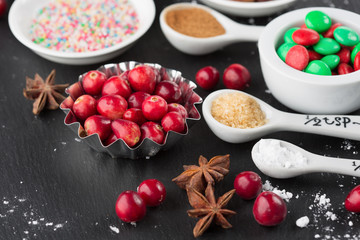 Christmas baking cupcake decorations and sprinkles, black background, top view. Holiday concept, winter time
