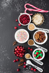 Christmas baking cupcake decorations and sprinkles, black background, top view. Winter holiday