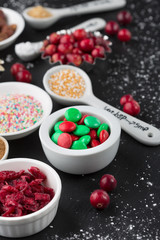 Christmas baking cupcake decorations and sprinkles, black background, selective focus. Holiday concept