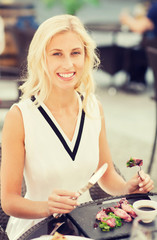 happy woman eating dinner at restaurant terrace