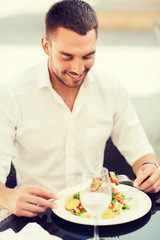 happy man eating salad for dinner at restaurant