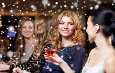 happy women with drinks at night club over snow