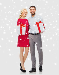 happy couple with christmas gift boxes over snow