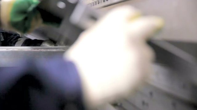 Worker hands bend metal sheet on a modern bending industrial machine at a factory. HD.
