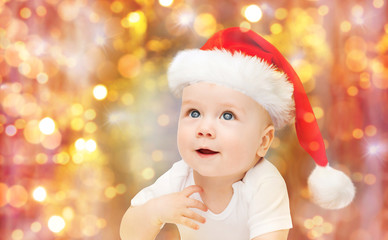 baby boy in christmas santa hat over blue lights